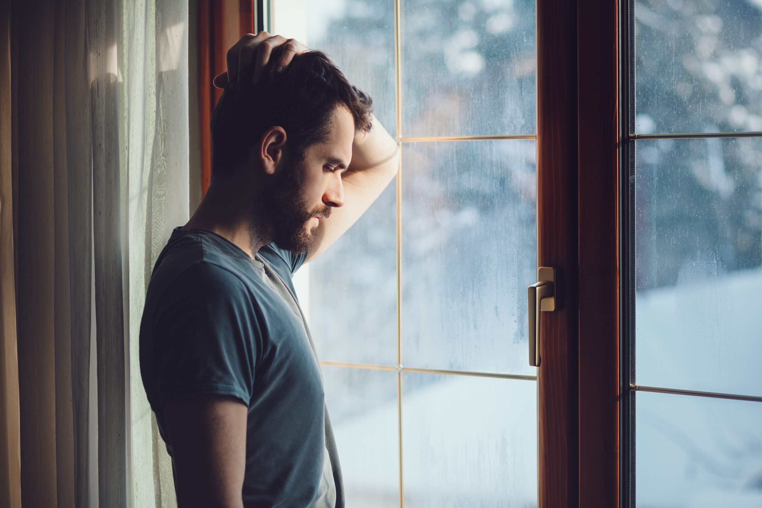 Man looking forlorn next to a window