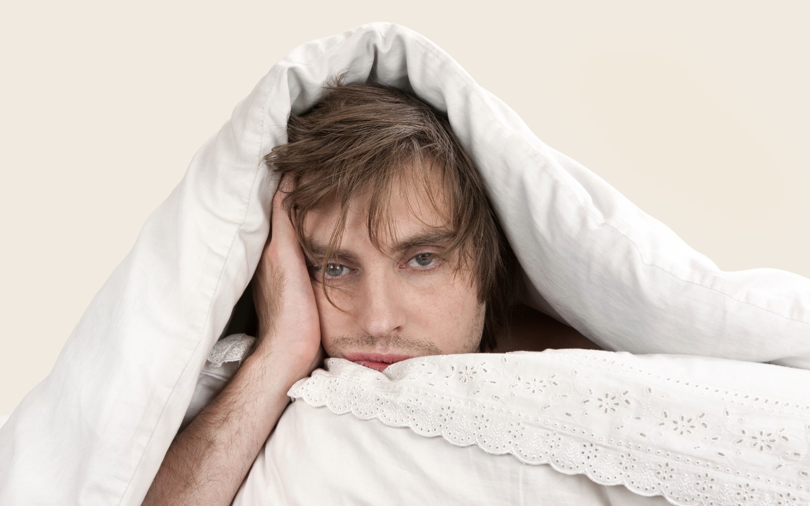 man looking tired under covers